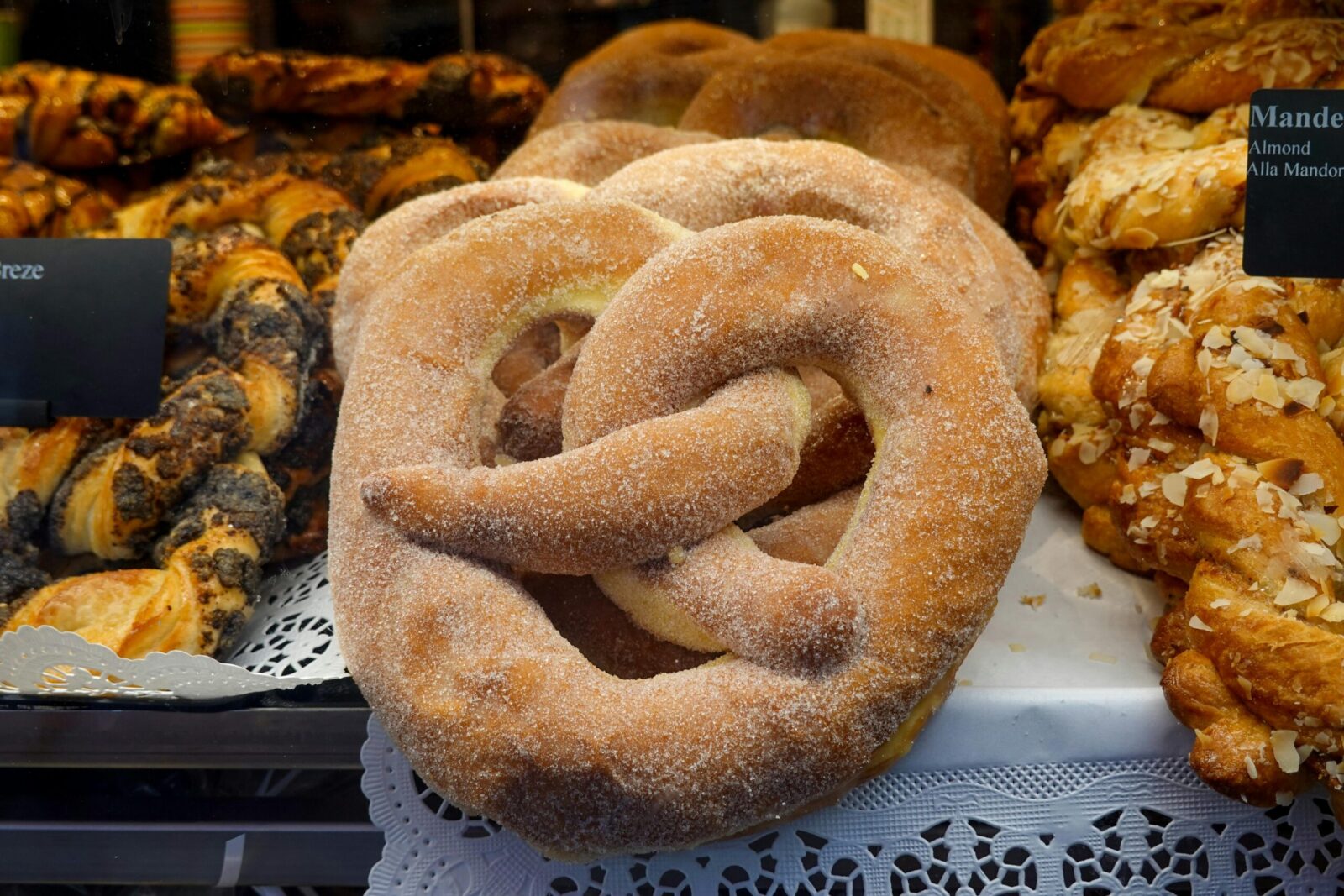 Close-up of fresh pretzels and pastries in a bakery display, showcasing texture and variety.
