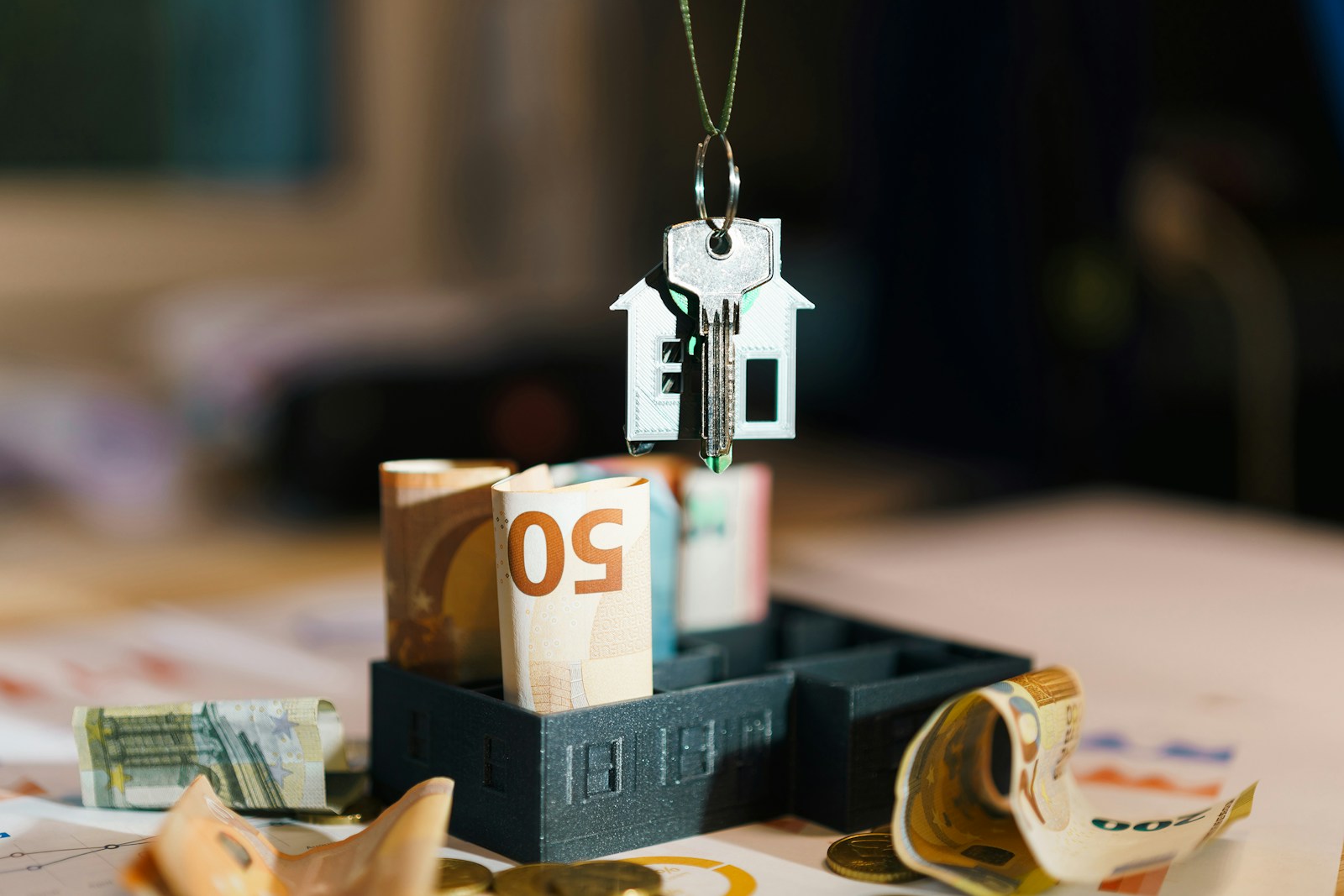 A house hanging from a string on top of a pile of money